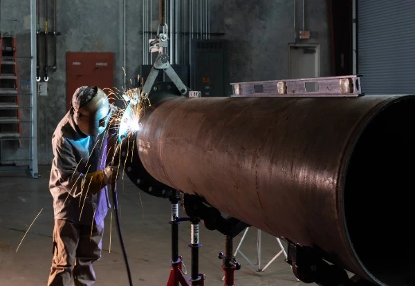Welding B31.1 Piping. A photo of a welder welding on some pipe